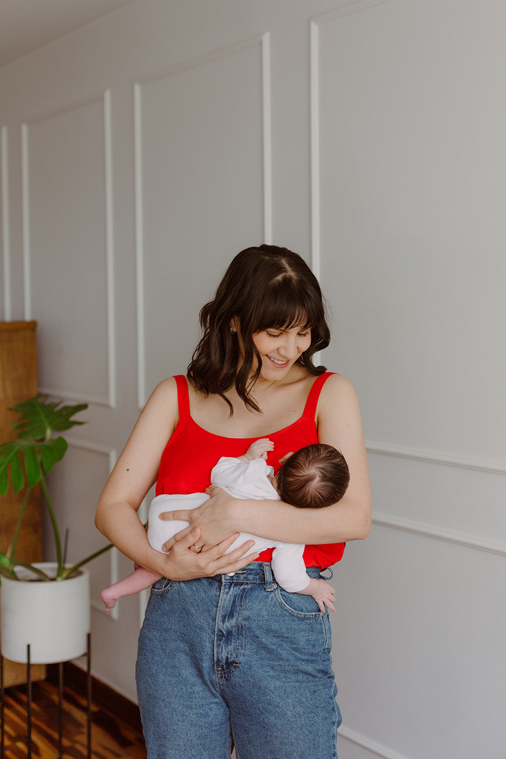 Mujer cargando un bebe usando una blusa color rojo.