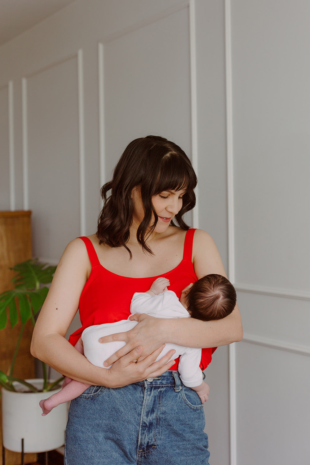 Mujer cargando un bebe usando una blusa color rojo.