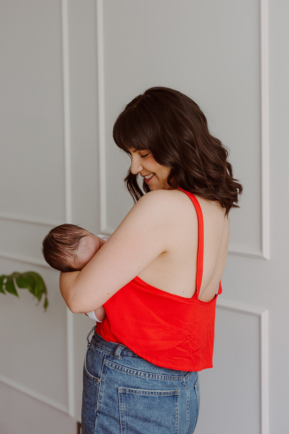 Mujer cargando un bebe usando una blusa color rojo.