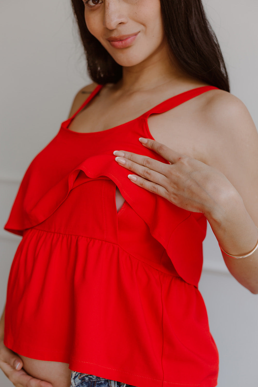 Una mujer embarazada usando una blusa color rojo.