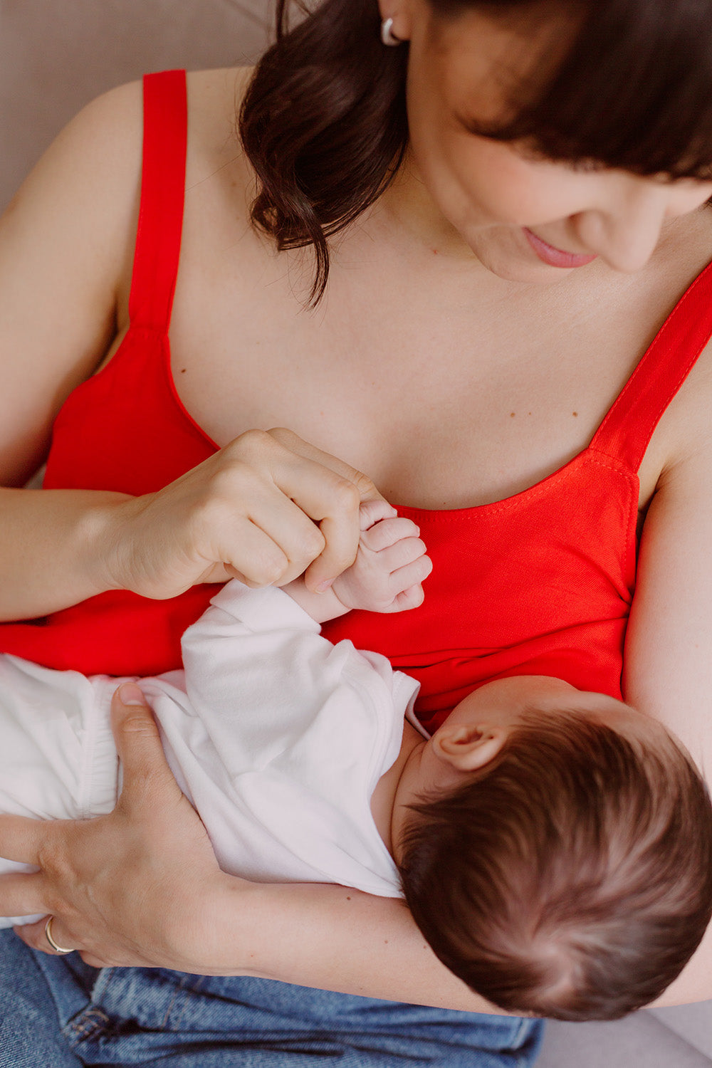 Mujer cargando un bebe usando una blusa color rojo.