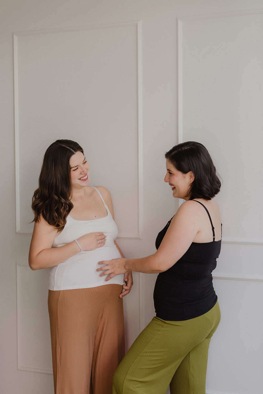 Dos mujeres sonriendo. Una está embarazada y utiliza un bividi blanco y la otra usa un bividi negro.
