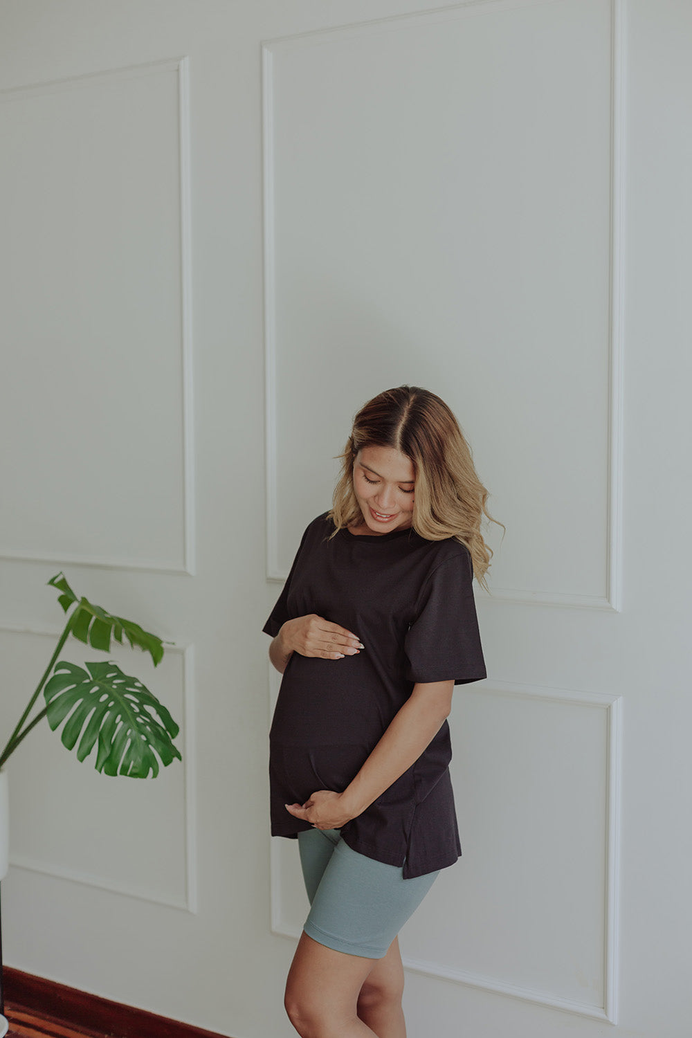 Mujer embarazada usando un biker short color verde cemento.
