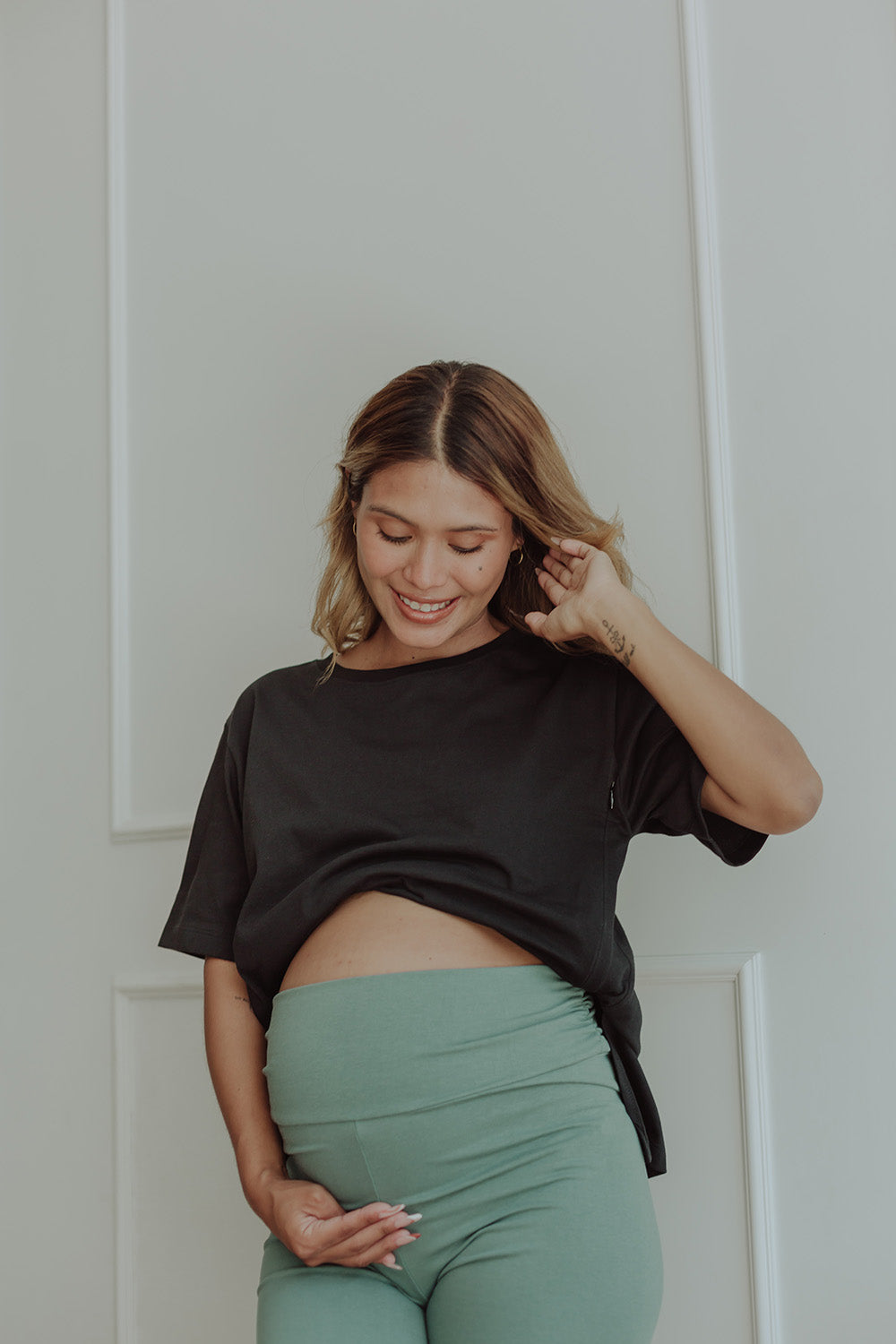 Mujer embarazada usando un biker short color verde cemento.