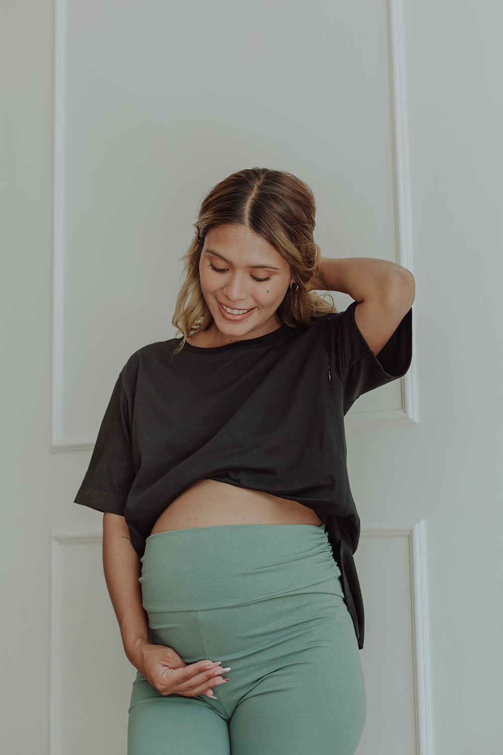 Mujer embarazada usando un biker short color verde cemento.