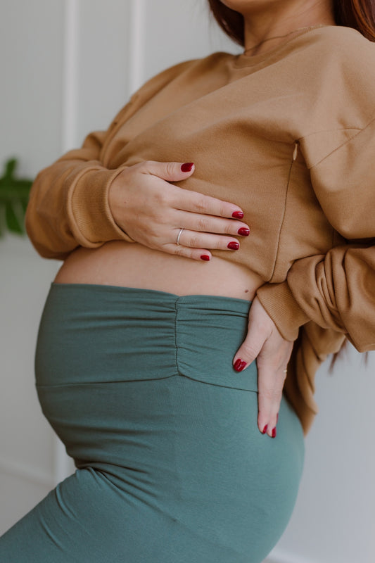 Mujer embarazada usando un biker short color dark green.