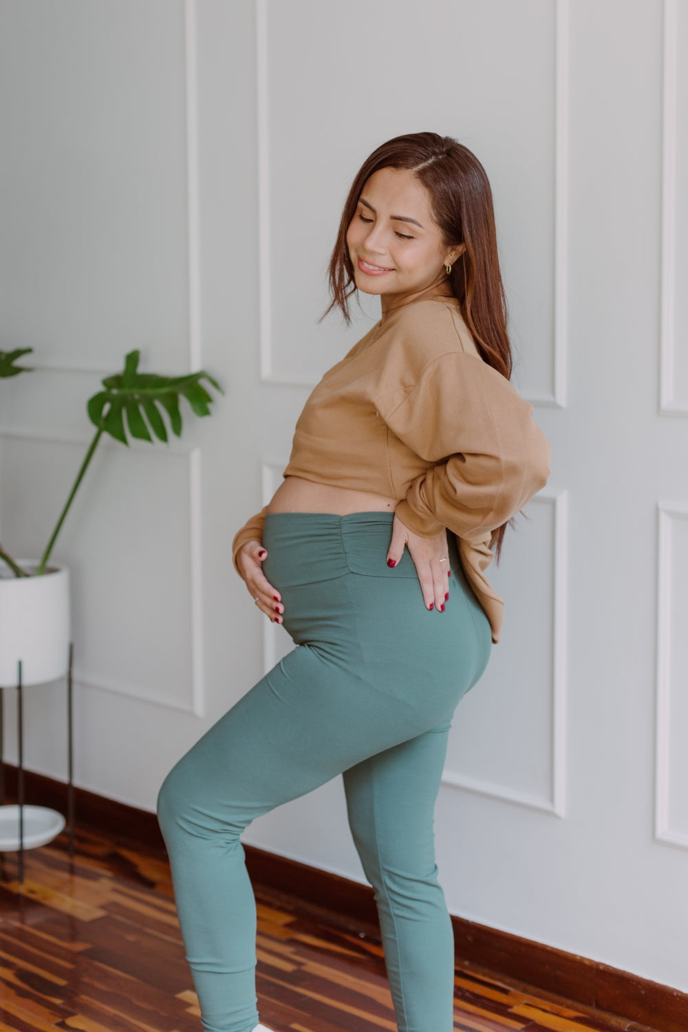 Mujer embarazada usando unos leggins en color dark green.