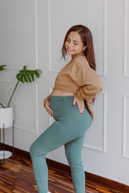 Mujer embarazada usando unos leggins en color dark green.