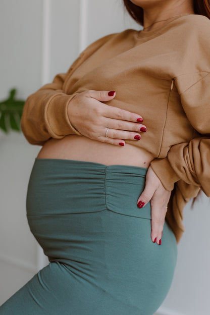 Mujer embarazada usando unos leggins en color dark green.