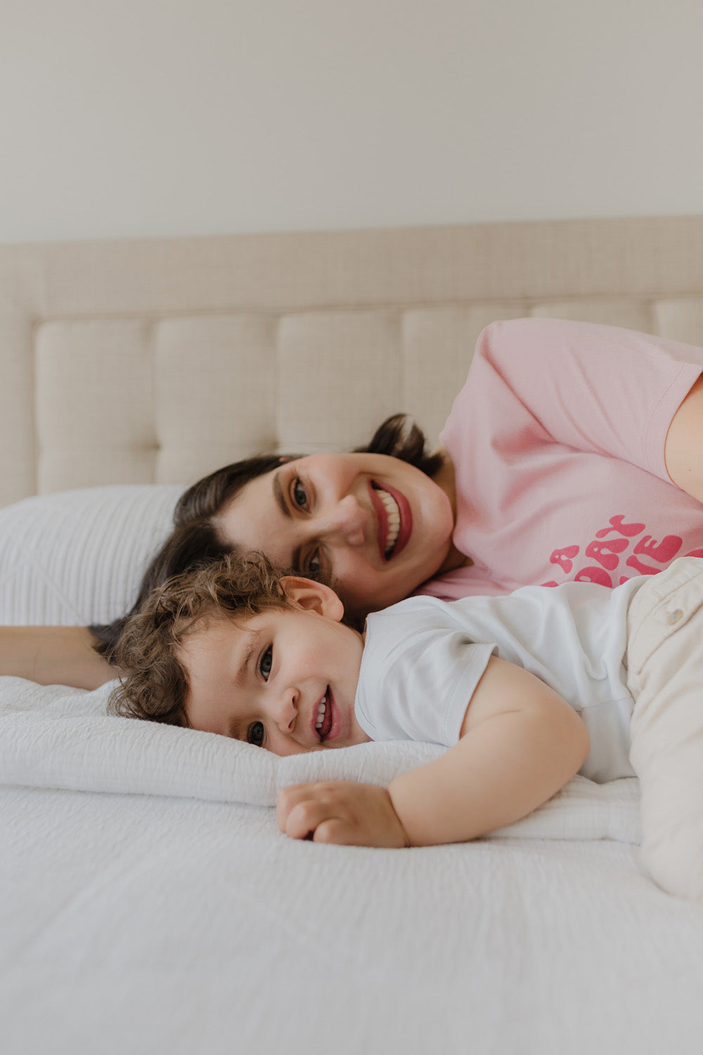 Mujer echada en una cama con un niño. La mujer usa un maxi polo color palo rosa.