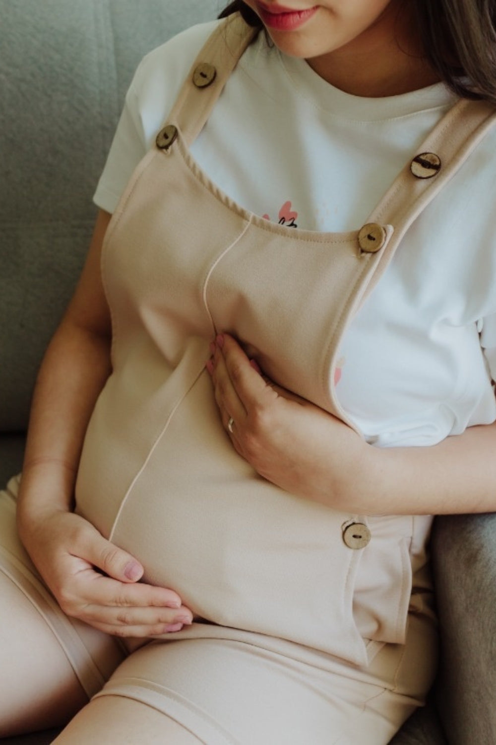 Mujer embarazada usando un overol short en color beige.