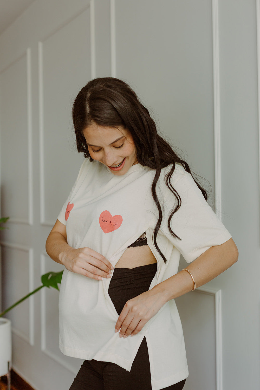 Mujer embarazada usando un polo color blanco con dos corazones rojos. 