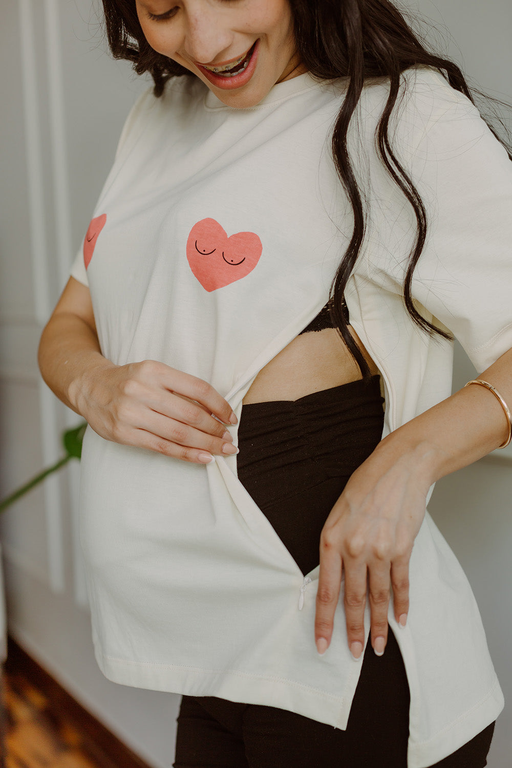 Mujer embarazada usando un polo color blanco con dos corazones rojos. 