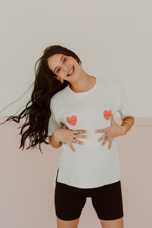 Mujer embarazada usando un polo color blanco con dos corazones rojos. 
