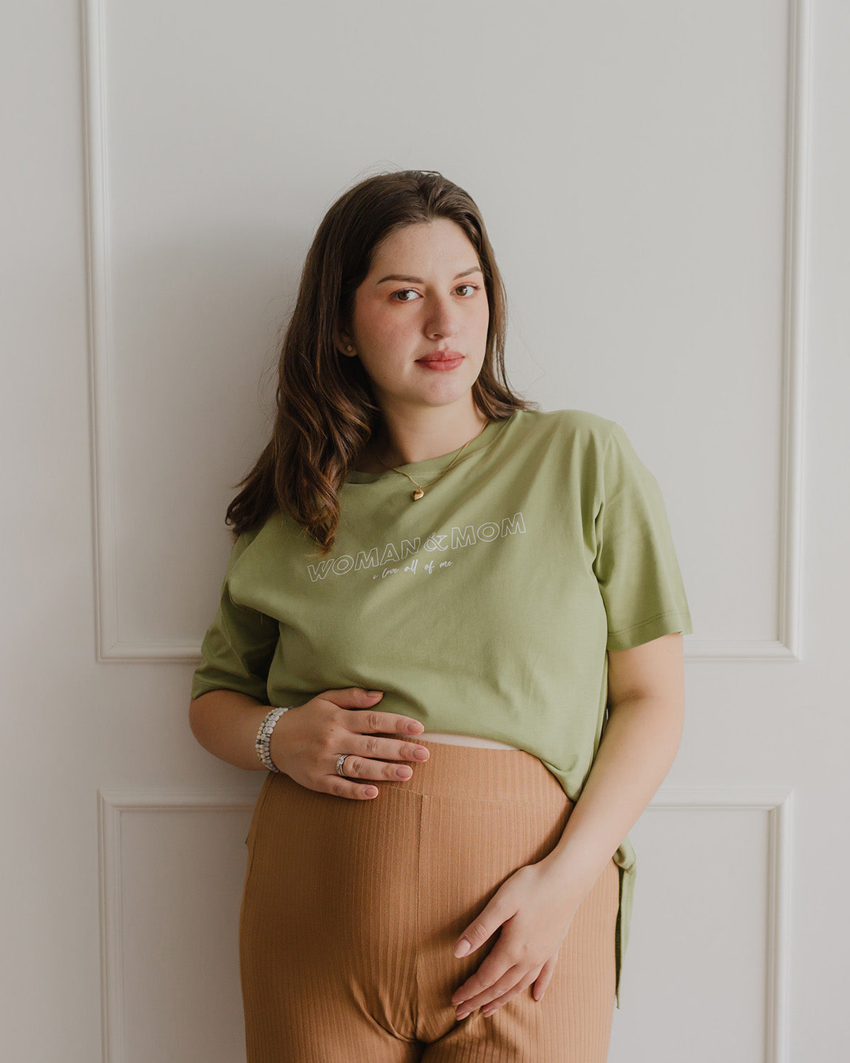 Una mujer embarazada usando un polo color mosstone.